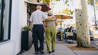 Älteres Paar spaziert auf dem Bürgersteig