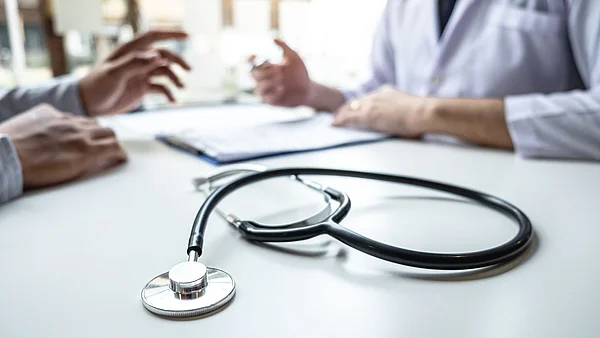 Arzt erklärt einem Patienten die Untersuchungsergebnisse, Abhörgerät im Vordergrund