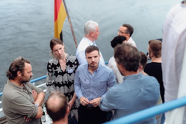 Foto von Personen auf einem Ausflugsschiff mit Wasser im Hintergrund.