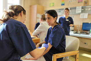 Zwei Studentinnen üben aneinander die korrekte Venenpunktion.
