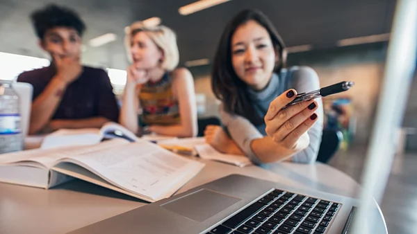 Studierende zeigen auf einen Laptop
