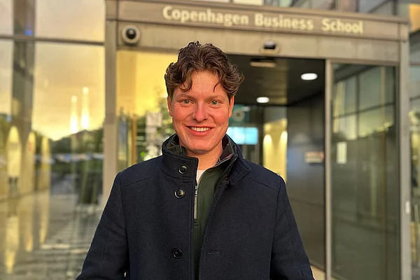 Porträt eines Mannes vor einem Gebäude mit Glastüren.