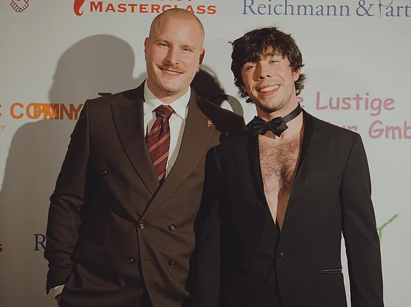 Julian Seitlinger und Adrian Parpat posieren für ein Foto vor einer Werbetafel.