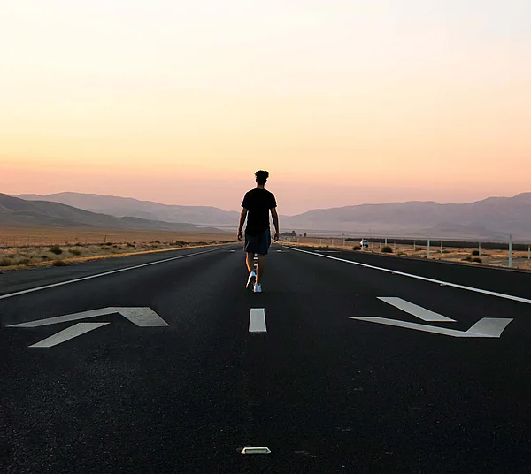 Ein junger Mann läuft auf einer zweispurigen Straße.