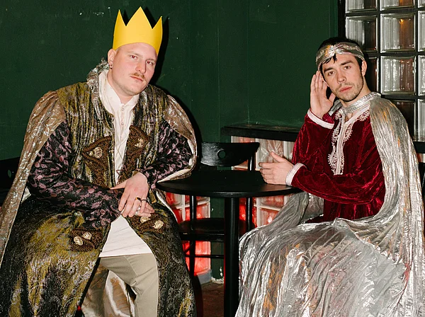 Julian Seitlinger und sein Geschäftspartner sitzen als Könige verkleidet an einem Tisch.